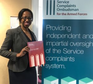 woman standing next to a poster holding a book